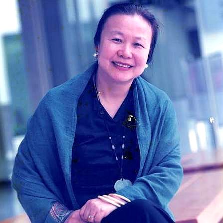 監製謝小韞身披藍綠色披肩，坐在戶外微笑