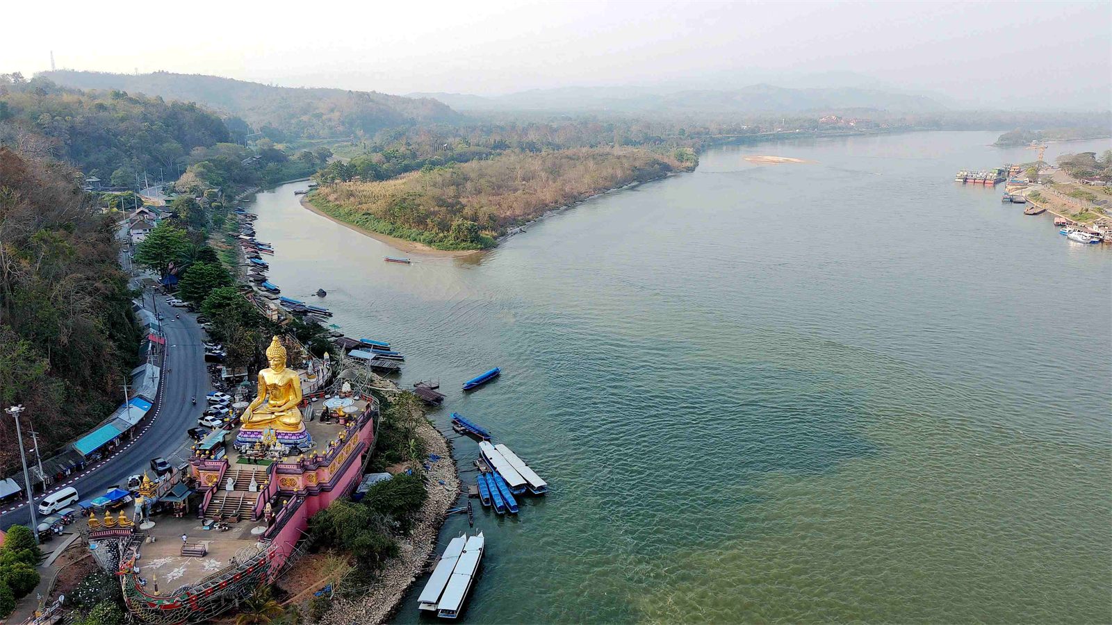 空拍金三角湄公河畔，河岸邊的金色大佛與停靠的長尾船